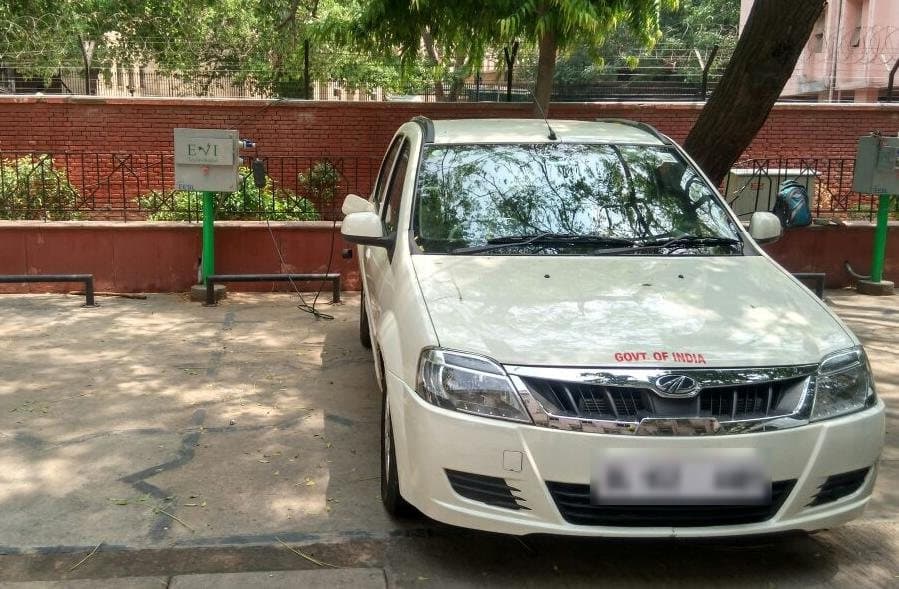 Government of India electric car parked beside a pole-mounted EVIT charger
